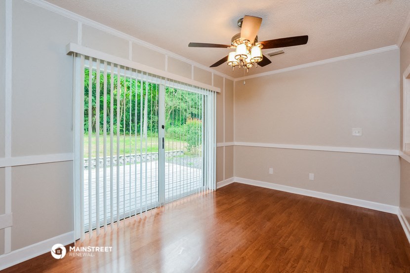 an empty living room with a sliding glass door and a ceiling fan