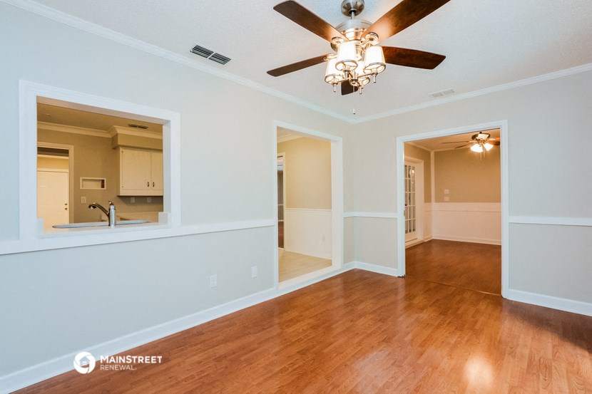 the living room and dining room of an empty house with a ceiling fan