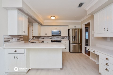 a large white kitchen with stainless steel appliances and white cabinets