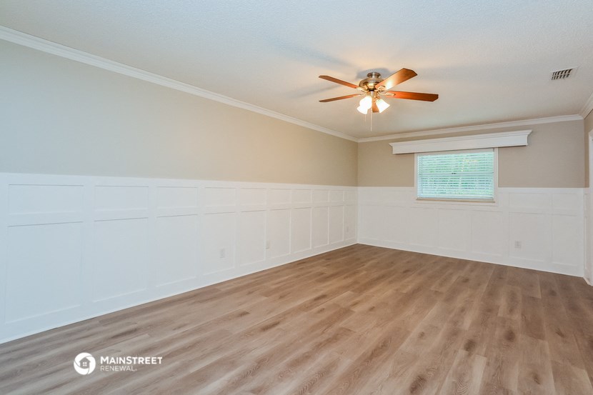 the spacious living room with wood flooring and a ceiling fan