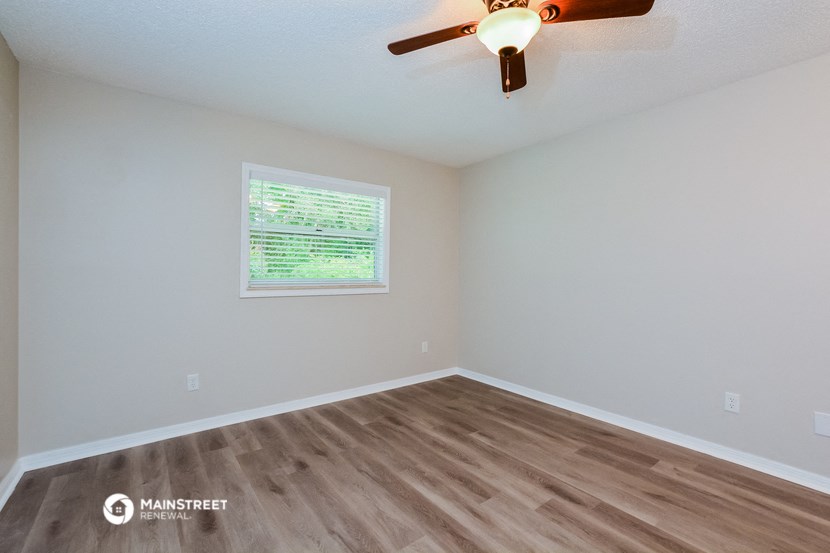 the spacious living room with hardwood floors and a ceiling fan