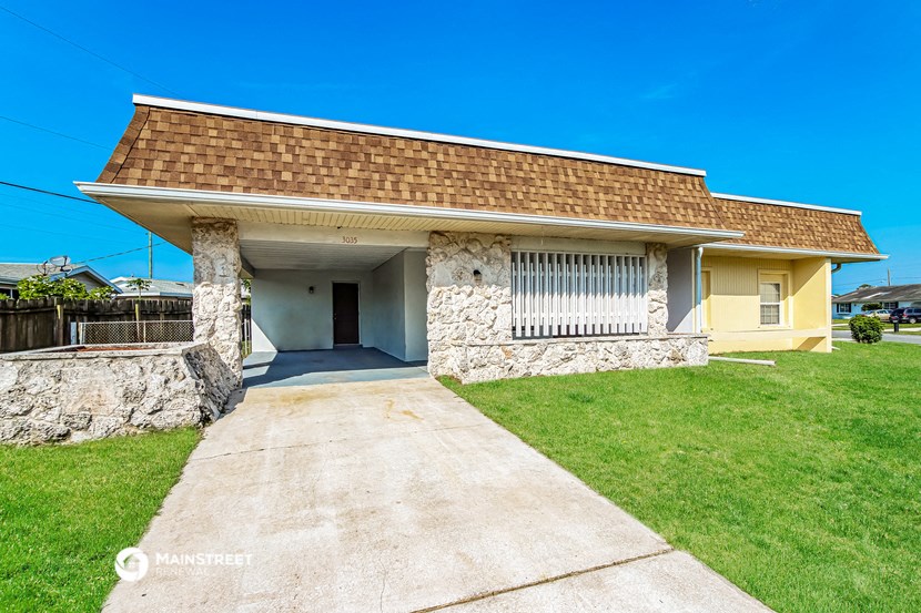 a small yellow house with a concrete driveway and grass