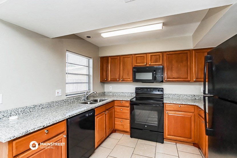 the kitchen has granite counter tops and black appliances
