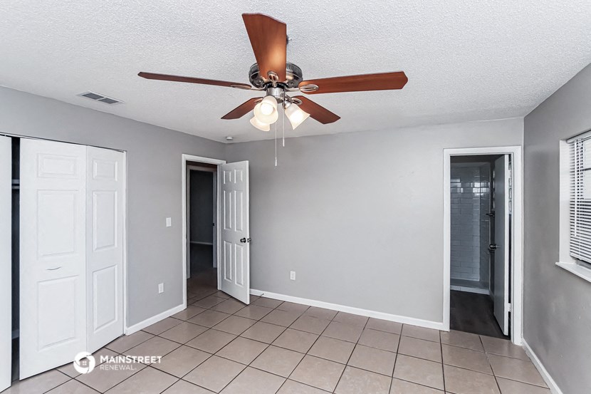 the living room has a ceiling fan and a tiled floor