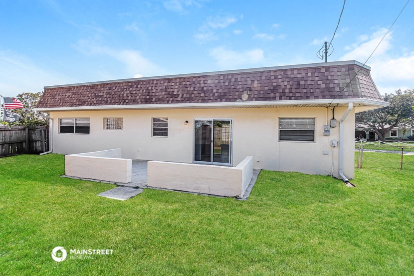 a small white house with a porch and a grassy yard