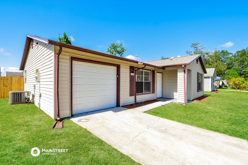 a small white and brown house with a driveway and a garage door