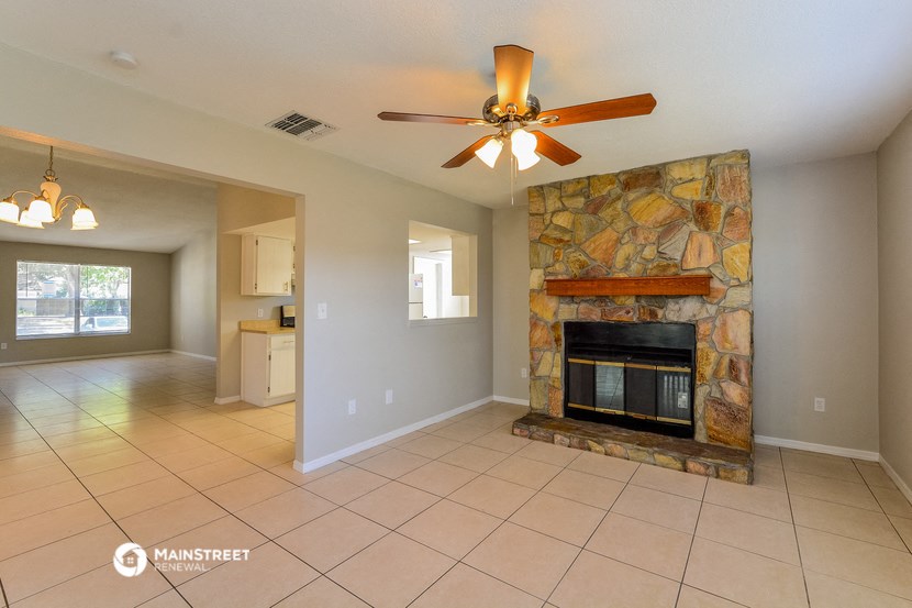 the living room has a stone fireplace and tile flooring