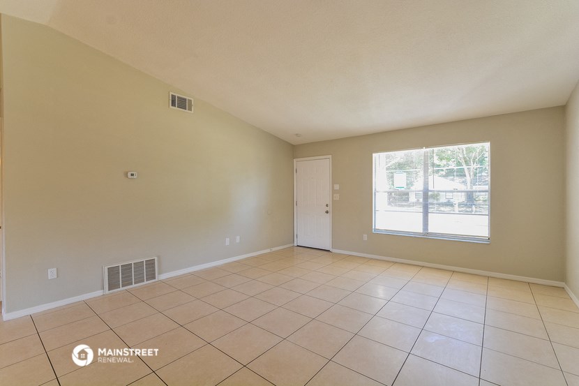 the living room of a house with tiled floors and a large window