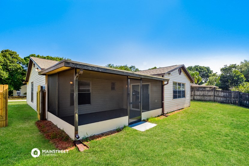 a small white house with a backyard and a porch