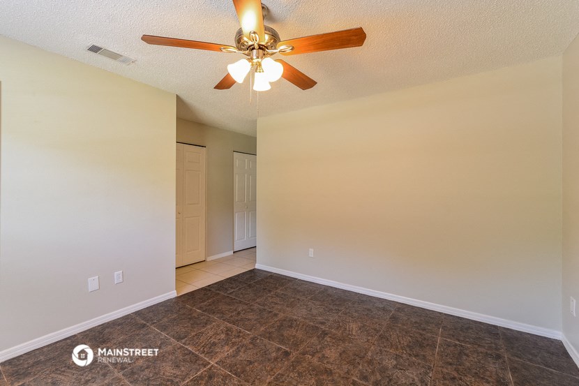 the spacious living room with ceiling fan and tile flooring