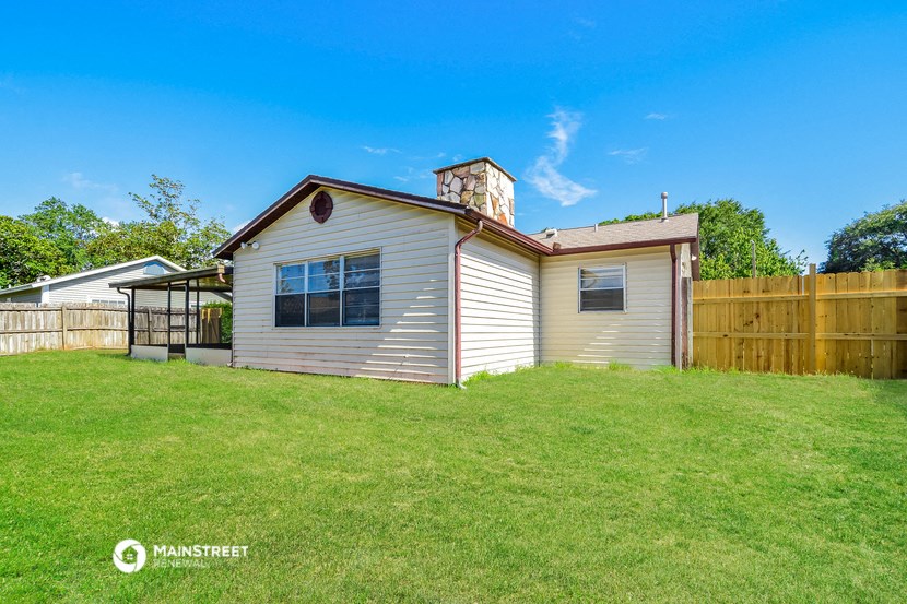 a small white house with a backyard and a wooden fence