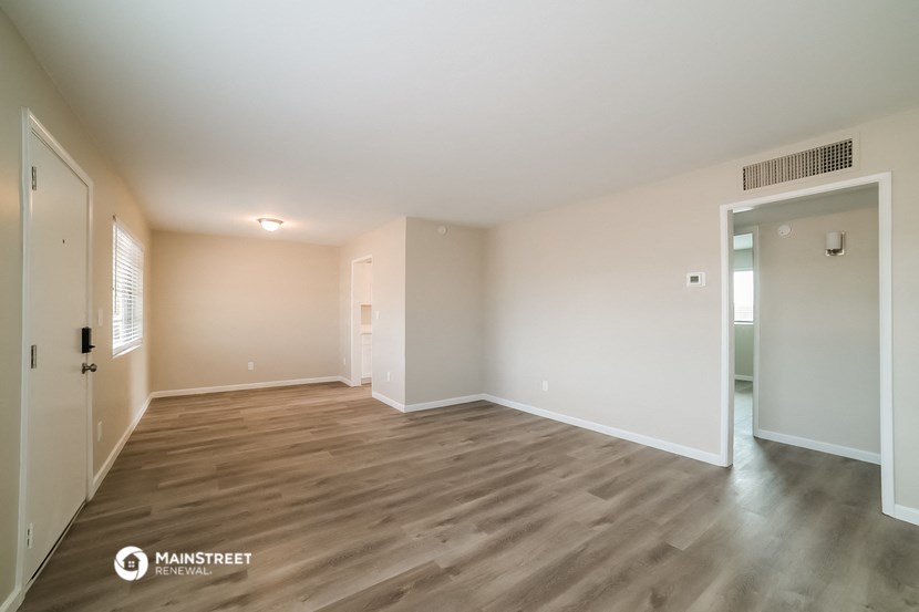 a spacious living room with wood flooring and white walls