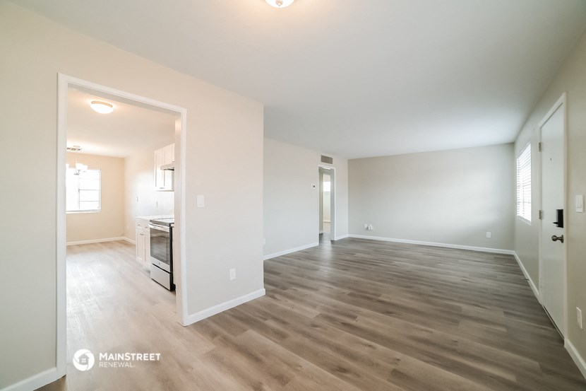 the living room and kitchen of an apartment with wood flooring