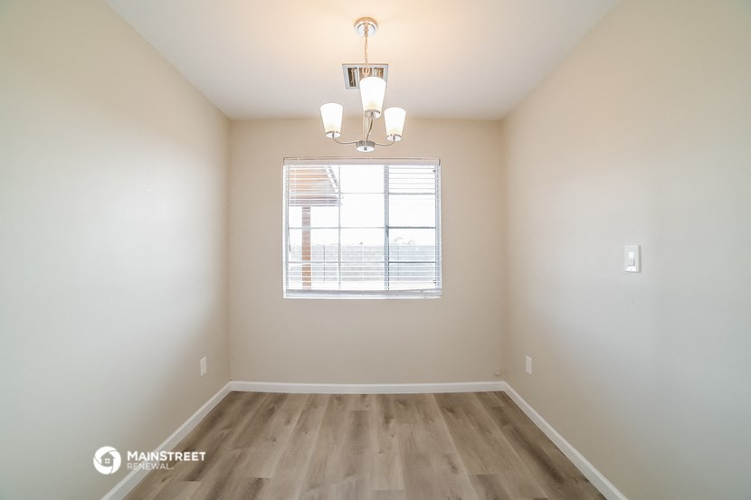 an empty room with a window and a chandelier