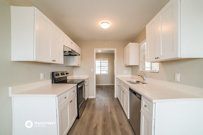 a large kitchen with white cabinets and white counter tops and white appliances
