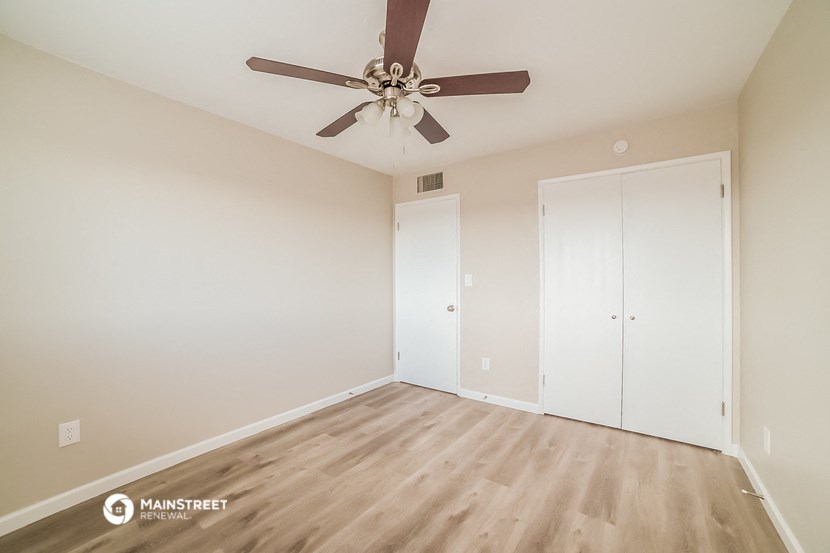 a bedroom with white walls and a ceiling fan