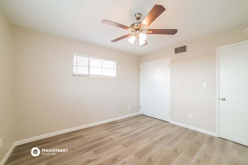 the spacious living room with wood flooring and a ceiling fan