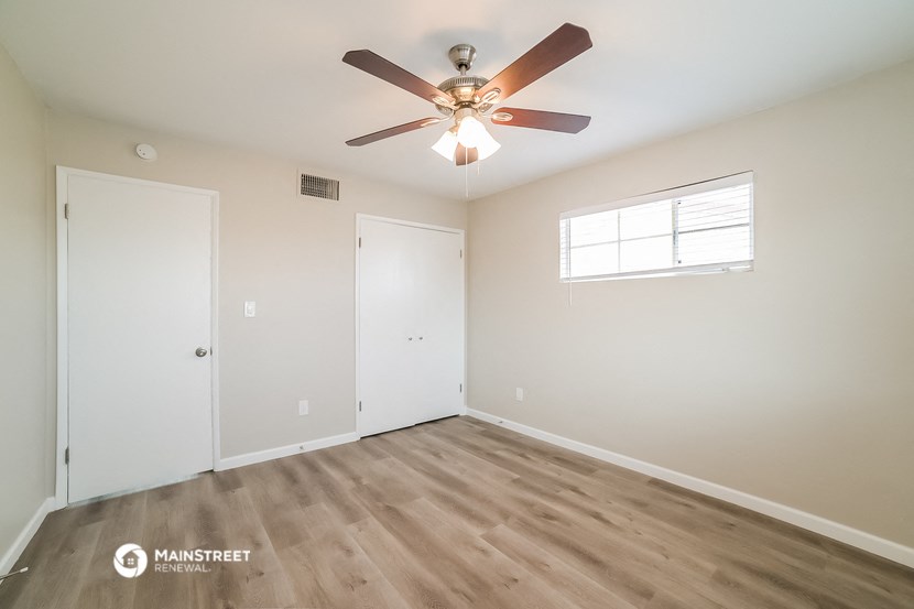 a bedroom with a ceiling fan and a door and a window