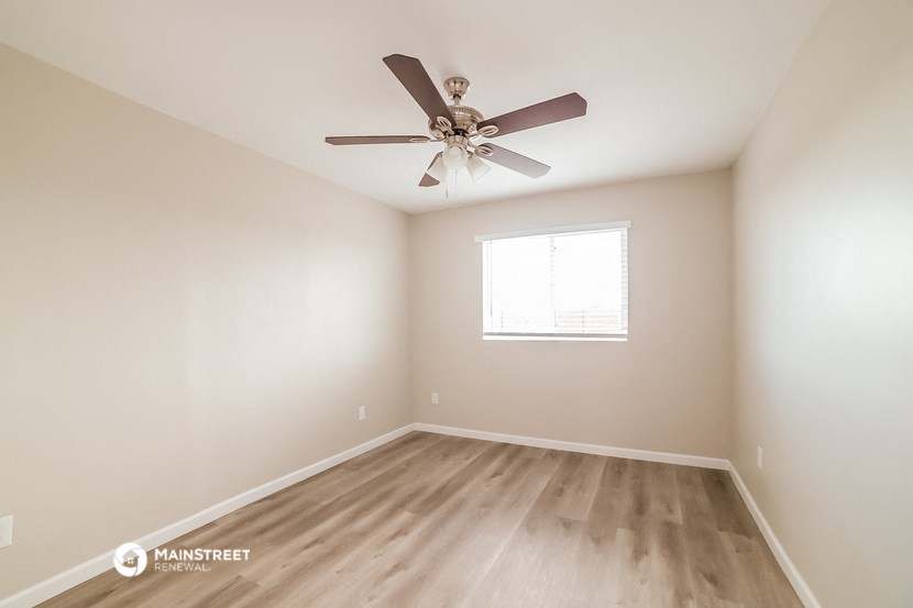 the spacious living room with ceiling fan and wood flooring