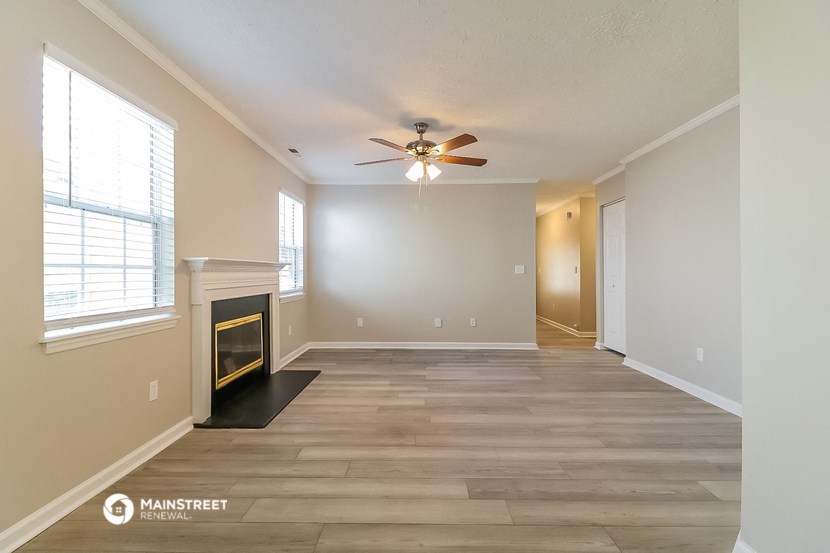 an empty living room with a fireplace and a ceiling fan