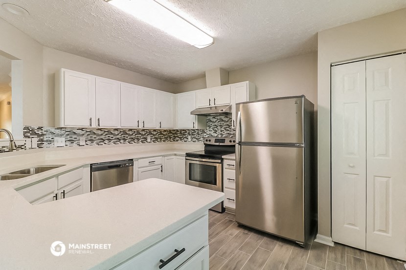 a kitchen with white cabinets and a stainless steel refrigerator