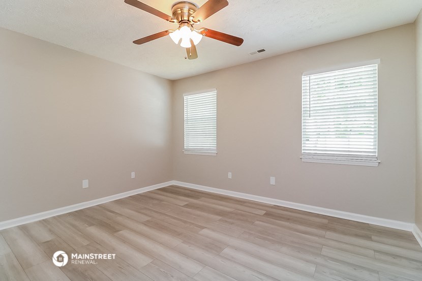 the spacious living room with hardwood floors and a ceiling fan