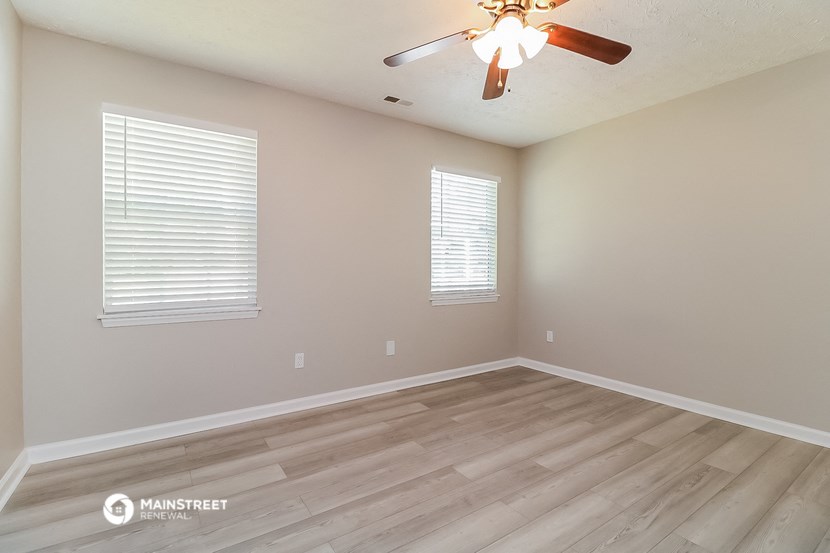 the spacious living room with hardwood floors and a ceiling fan