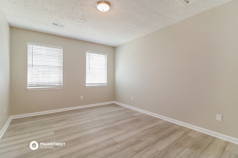 the spacious living room with hardwood flooring and two windows