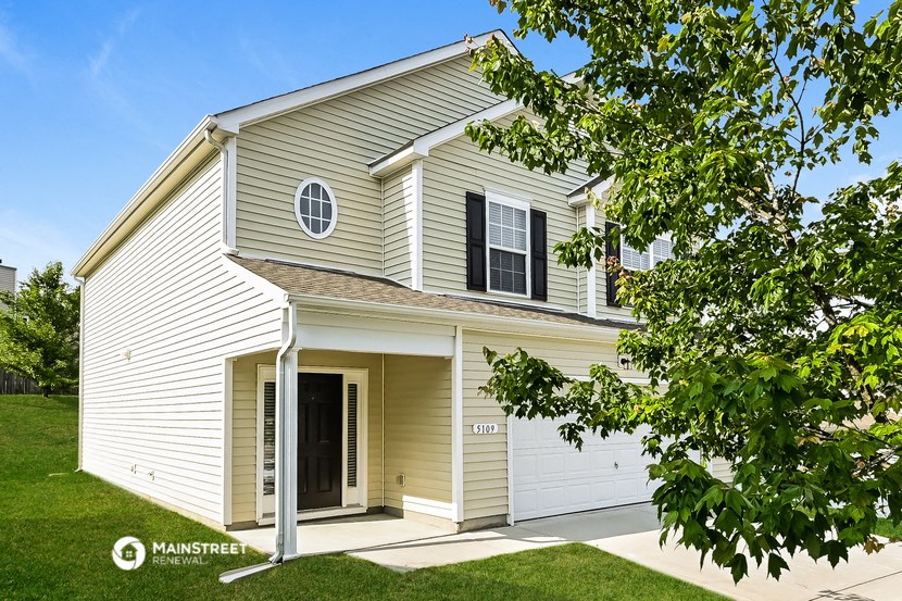 a white house with a garage and a tree