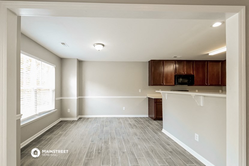 an empty living room and kitchen with wood flooring and a window