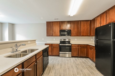 a kitchen with wooden cabinets and black appliances and a sink