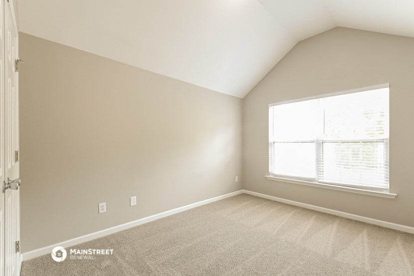 a bedroom with a large window and a carpeted floor