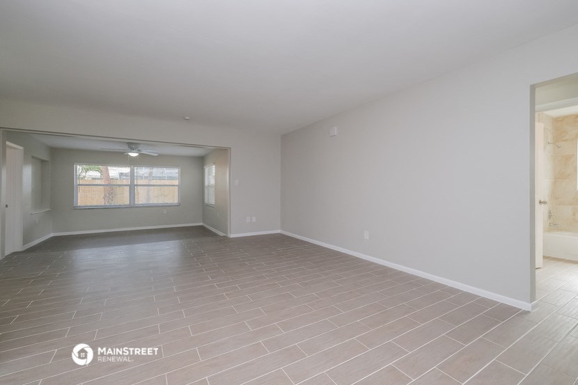 the living room of an empty house with a tile floor and a window