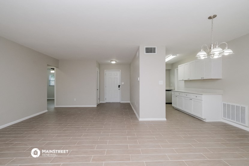 an empty kitchen and living room with white cabinets and a tile floor