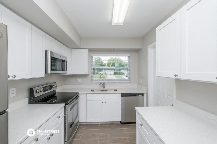 a white kitchen with white cabinets and a window