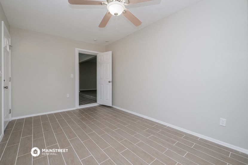 the living room of an empty house with a ceiling fan