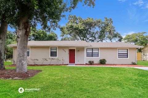 a white house with a red door and a tree