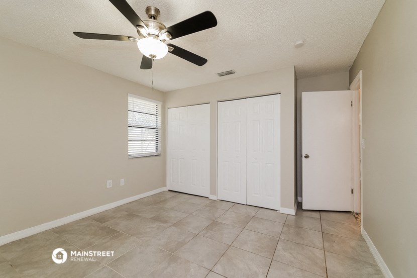 the spacious living room has a ceiling fan and tile flooring