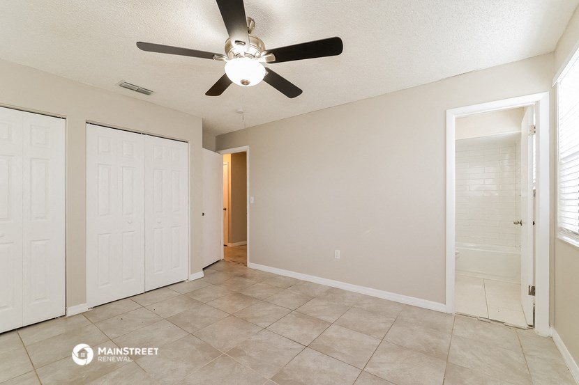 the spacious living room with ceiling fan and tile flooring