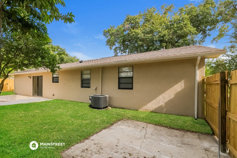 a tan house with a yard and a wooden fence