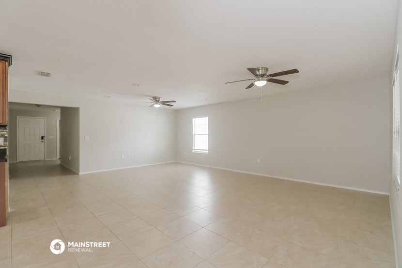 an empty living room with a ceiling fan