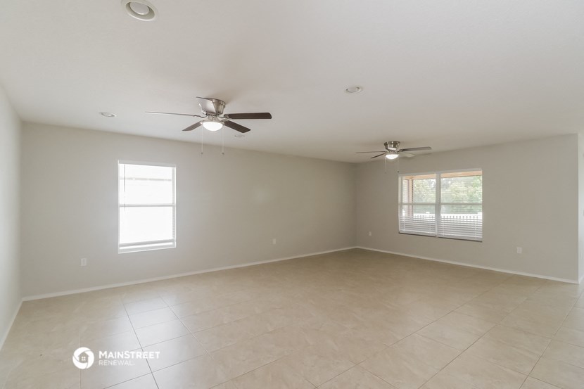 an empty living room with a ceiling fan