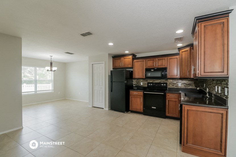 an empty kitchen with black appliances and wooden cabinets
