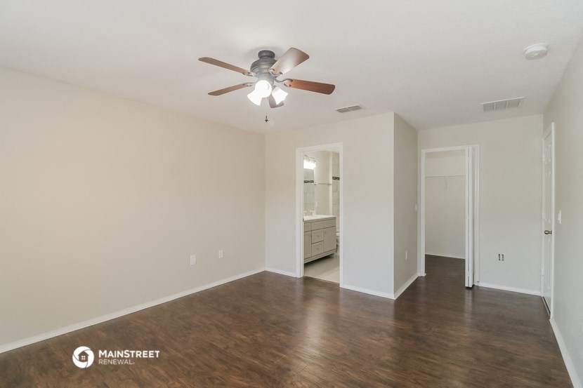 an empty living room with a ceiling fan and wood floors