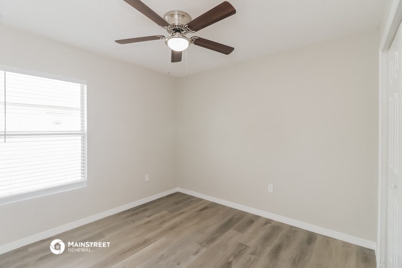 an empty bedroom with a ceiling fan and a window