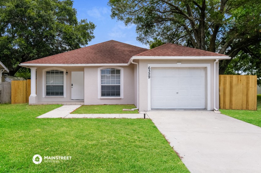 a small pink house with a lawn and a garage