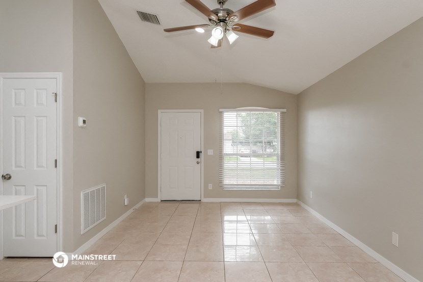 an empty living room with a ceiling fan and a window