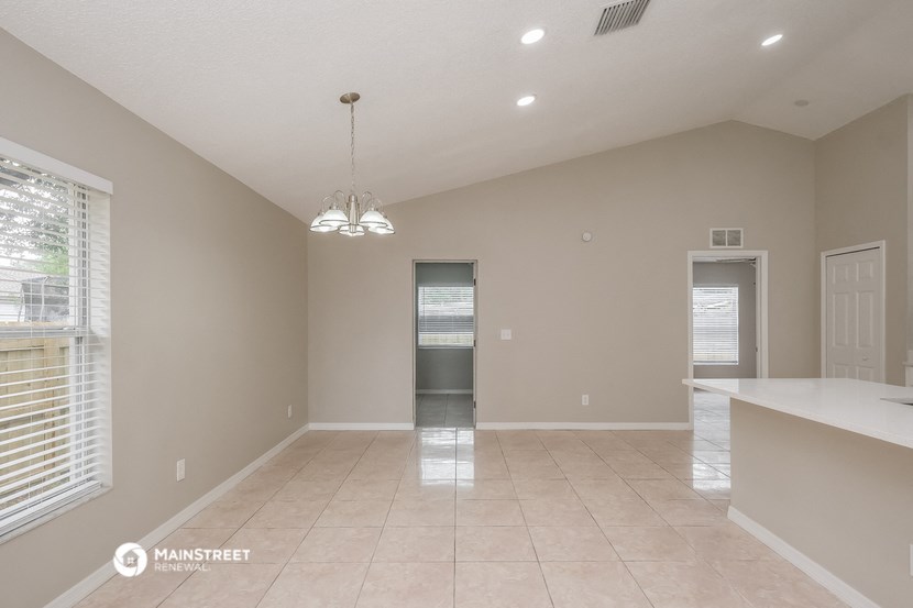an empty dining room with a kitchen and a door to the laundry room