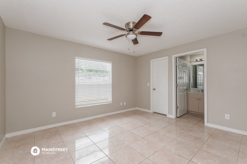 the spacious living room with ceiling fan and tile flooring
