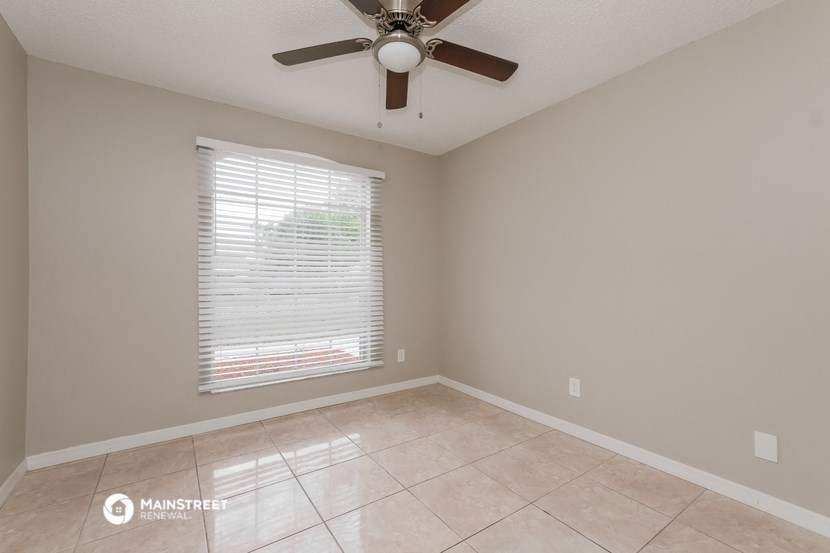 an empty living room with a ceiling fan and a window